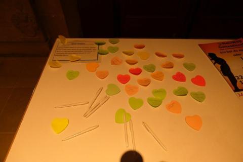 Auf einem Tisch kleben ganz viele beschriebene bunte Herzchen