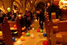 Menschen in der Kirche bücken sich nach bunten Luftballons im Gang